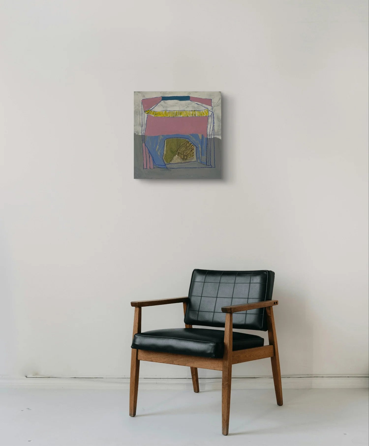 Black armchair in front of a colorful abstract painting on a white wall.