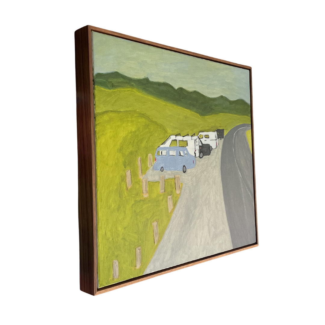 Framed artwork of a scenic road with vehicles and green hills.