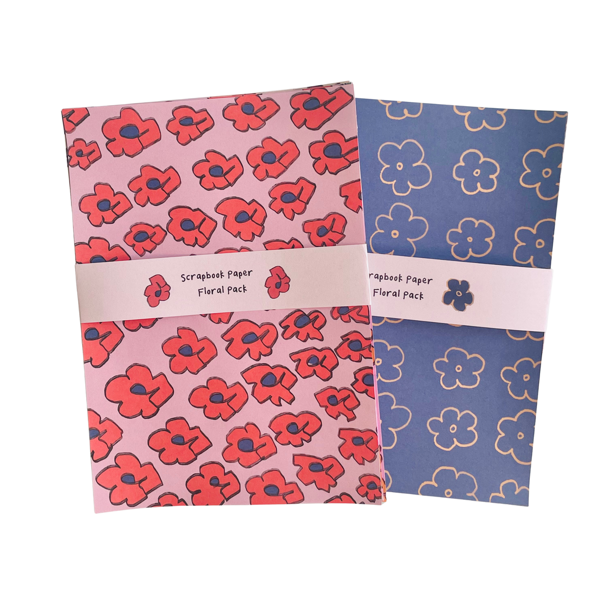 Two floral scrapbook paper sheets overlapping on a white background. The left sheet is light pink with red poppy flowers outlined in dark blue, and the right sheet is medium blue with white outlined flowers.