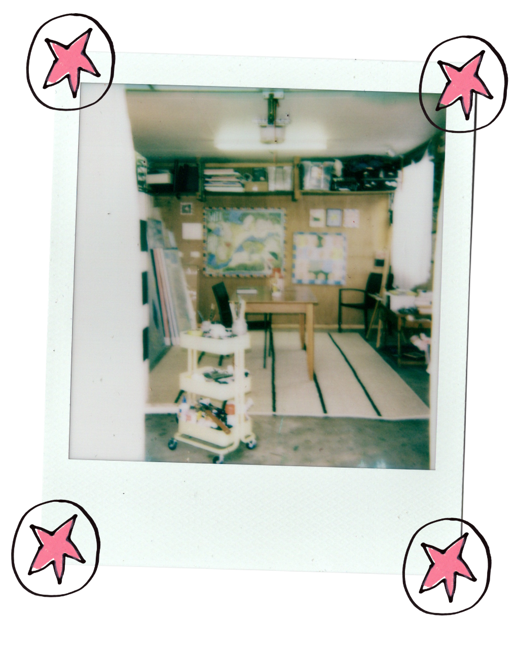 A Polaroid-style photo print showing an interior room with shelves, a desk, chairs, and a rug, framed by a white border with pink star illustrations in the corners.